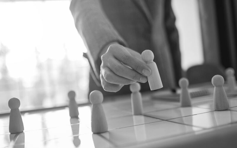 Businesswoman leader choosing wooden people from a group of empl